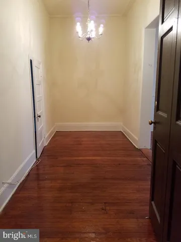 an empty room with wooden floor cabinet and windows