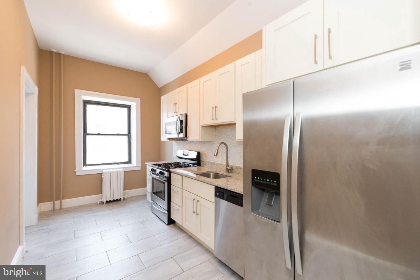 18 West Franklin Street Baltimore, MD 21201 - Photo 32 of 58 a kitchen with stainless steel appliances granite countertop a refrigerator a sink a stove and white cabinets