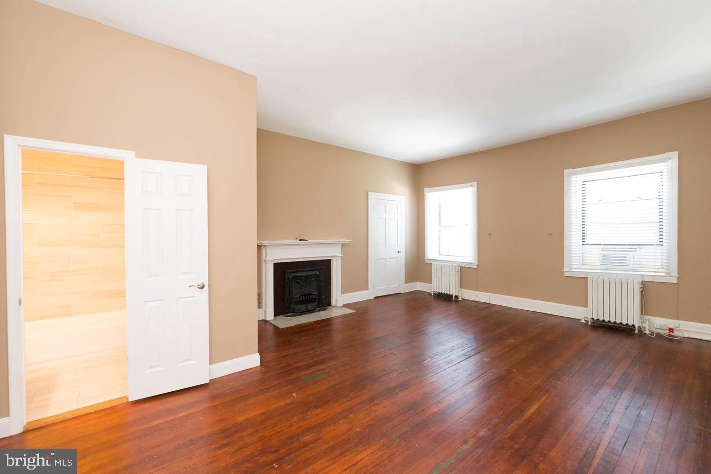 18 West Franklin Street Baltimore, MD 21201 - Photo 35 of 58 an empty room with wooden floor fireplace and windows