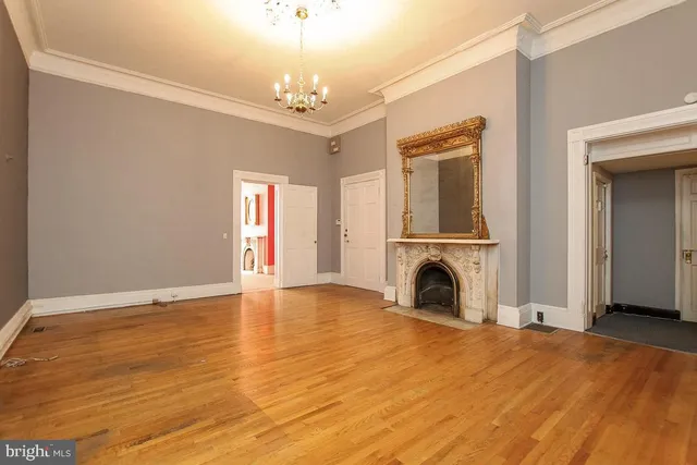 a view of a livingroom with a fireplace a chandelier and wooden floor