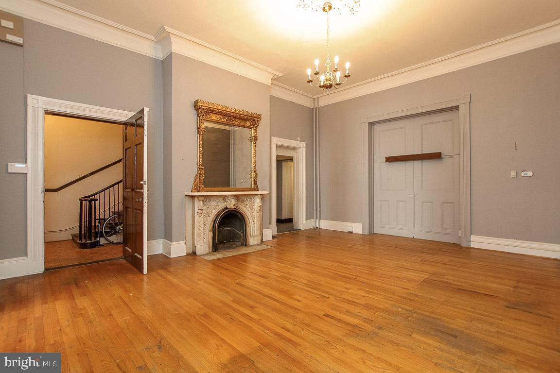 18 West Franklin Street Baltimore, MD 21201 - Photo 7 of 58 a view of a livingroom with a fireplace a chandelier a ceiling fan and wooden floor