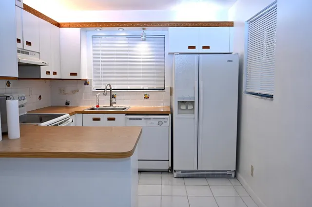 a kitchen with stainless steel appliances granite countertop a refrigerator a stove and a sink