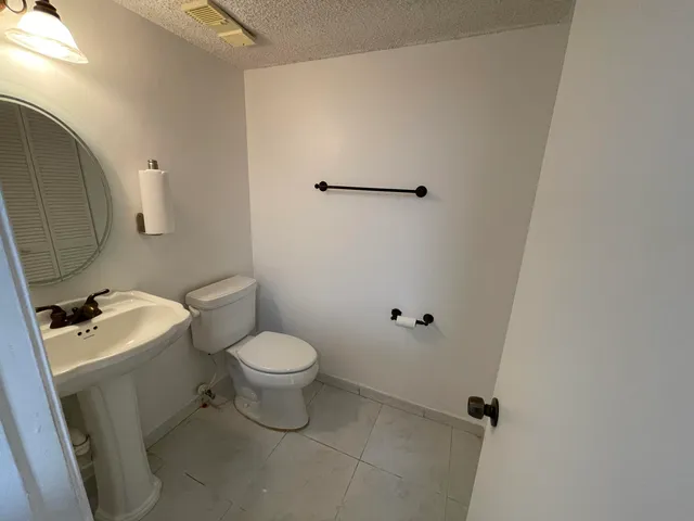 a white toilet sitting next to a white sink and vanity