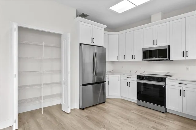 a kitchen with a refrigerator stove and white cabinets