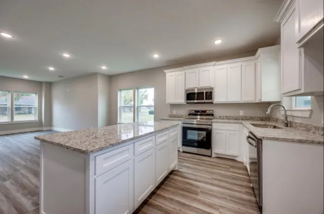 a kitchen with stainless steel appliances granite countertop a stove a sink and a microwave