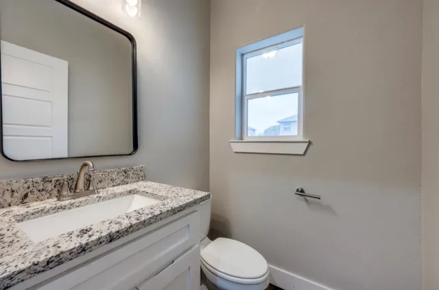 a bathroom with a granite countertop toilet a sink and mirror