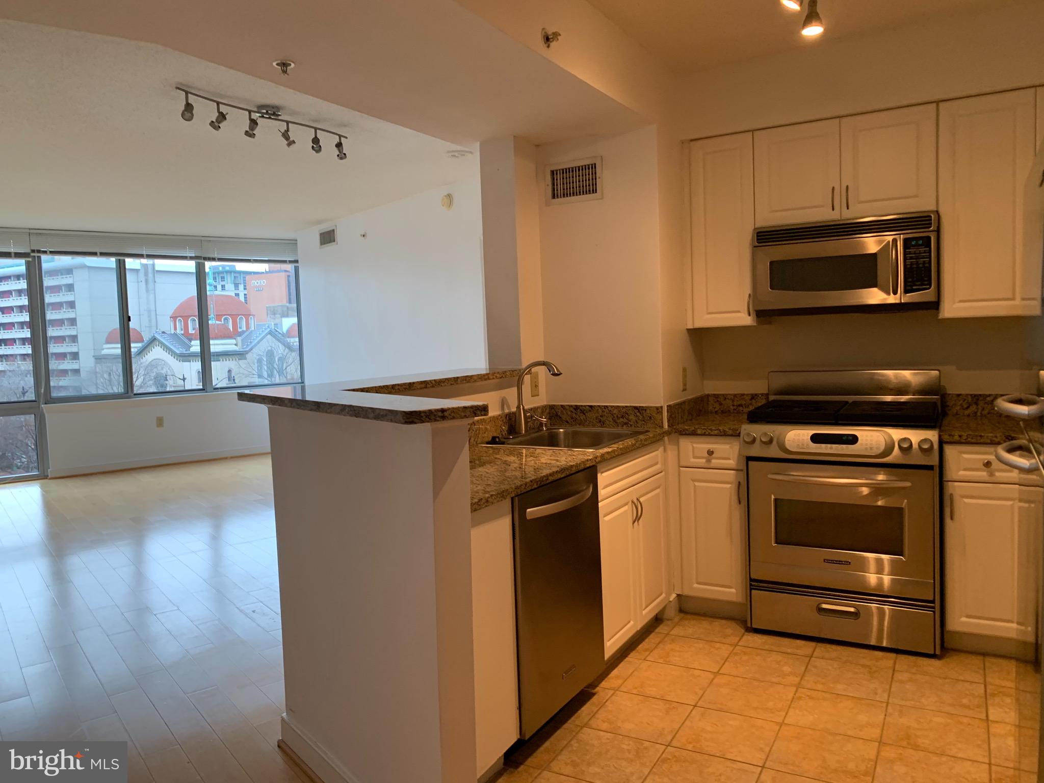555 Massachusetts Avenue Northwest, Unit 503 Washington, DC 20001 - Photo 7 of 24 a kitchen with stainless steel appliances granite countertop a stove and a microwave