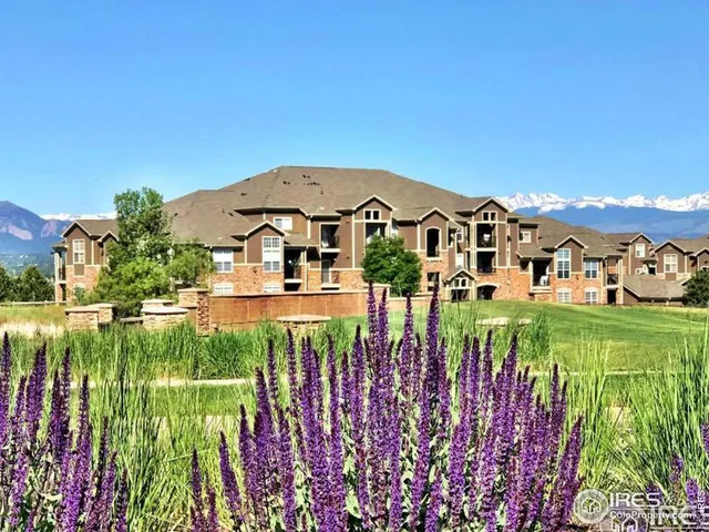 a view of a white house with a big yard plants and large trees
