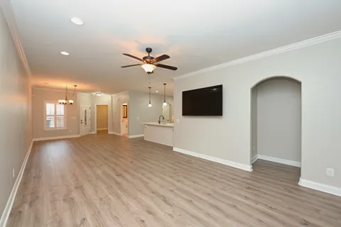 a view of a livingroom with a flat screen tv wooden floor and a ceiling fan