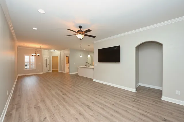 a view of a livingroom with a flat screen tv wooden floor and a ceiling fan