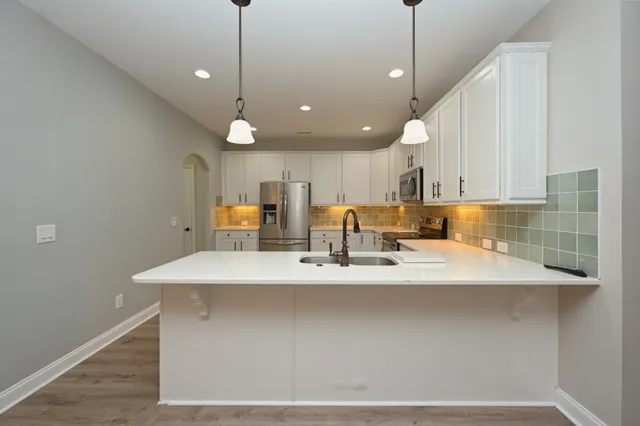 a room with kitchen island a sink and wooden floor