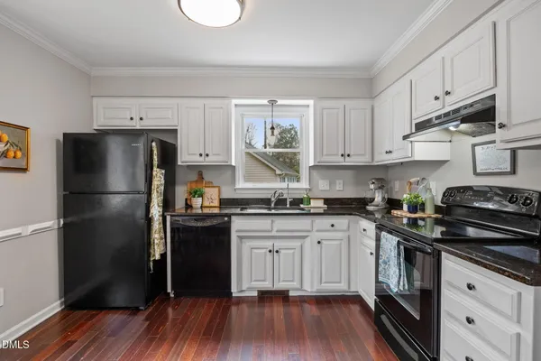 a kitchen with stainless steel appliances granite countertop a stove a refrigerator a sink dishwasher a dining table and chairs with wooden floor