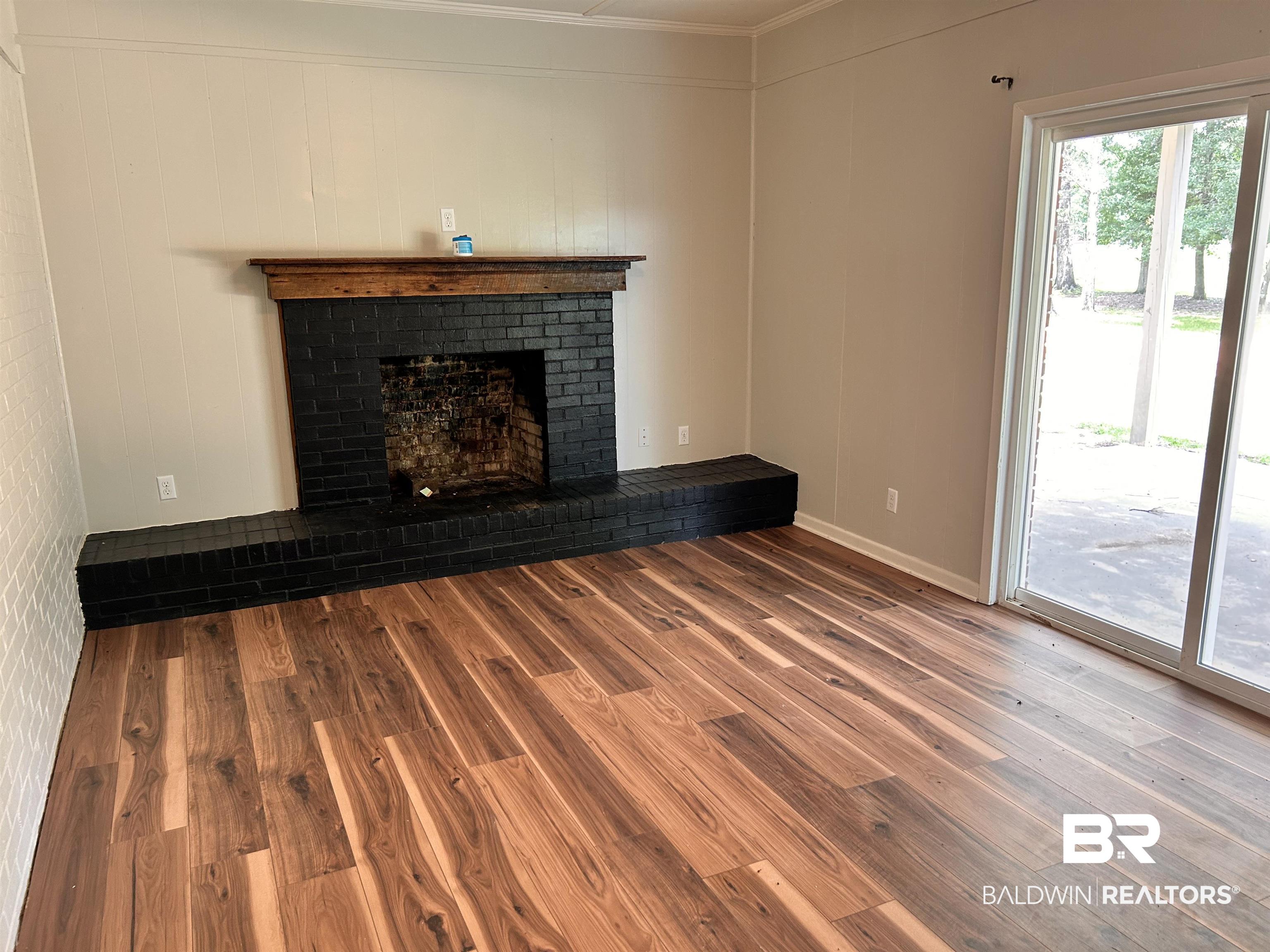 7870 Bradley Road Brewton, AL 36426 - Photo 5 of 8 Living space featuring a black brick fireplace with a wood mantel, wood-finish flooring, and a sliding glass door