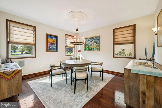 a dining room with wooden floor a chandelier a wooden table and chairs