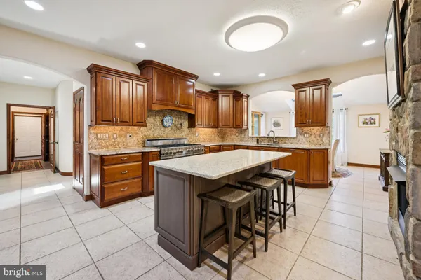 a kitchen with stainless steel appliances granite countertop a stove top oven a sink dishwasher and a refrigerator with wooden cabinets