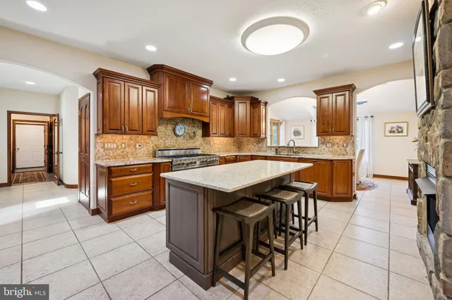 a kitchen with stainless steel appliances granite countertop a stove top oven a sink dishwasher and a refrigerator with wooden cabinets