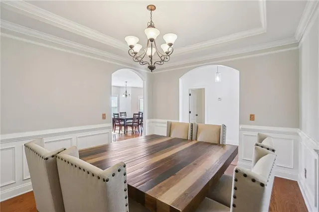 a dining room with wooden floor a chandelier a wooden table and chairs