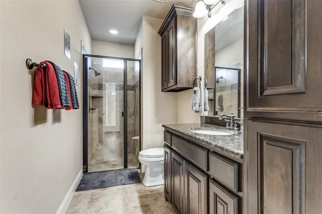 a bathroom with a granite countertop sink a toilet and shower