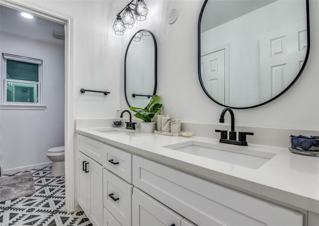 11211 McCree Road Dallas, TX 75238 - Photo 19 of 29 a bathroom with a sink a mirror and a toilet