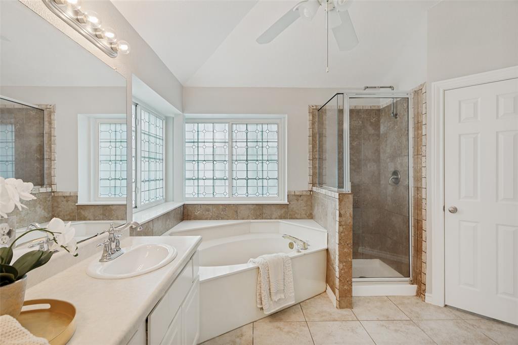 1228 Concho Drive Benbrook, TX 76126 - Photo 21 of 39 Bathroom featuring a corner soaking tub, a glass-enclosed shower with tiled walls, and a single vanity with an integrated sink