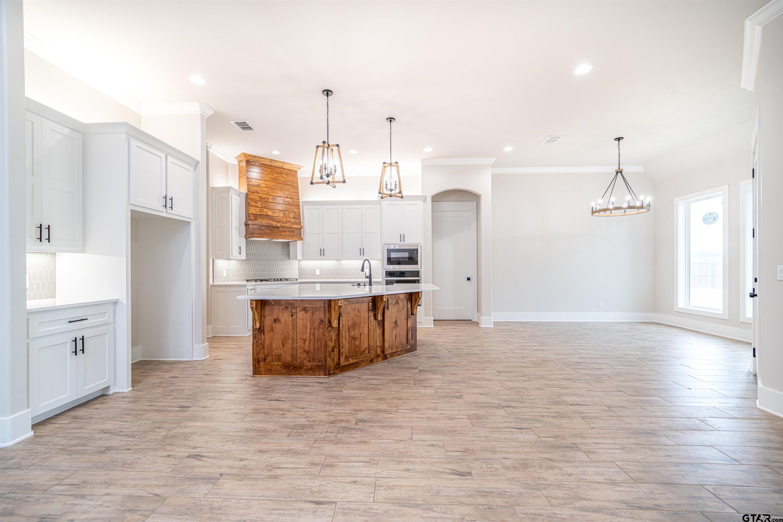 3910 Hidden Hills Circle Longview, TX 75605 - Photo 15 of 39 a large kitchen with kitchen island a stove a sink dishwasher and a refrigerator with wooden floor
