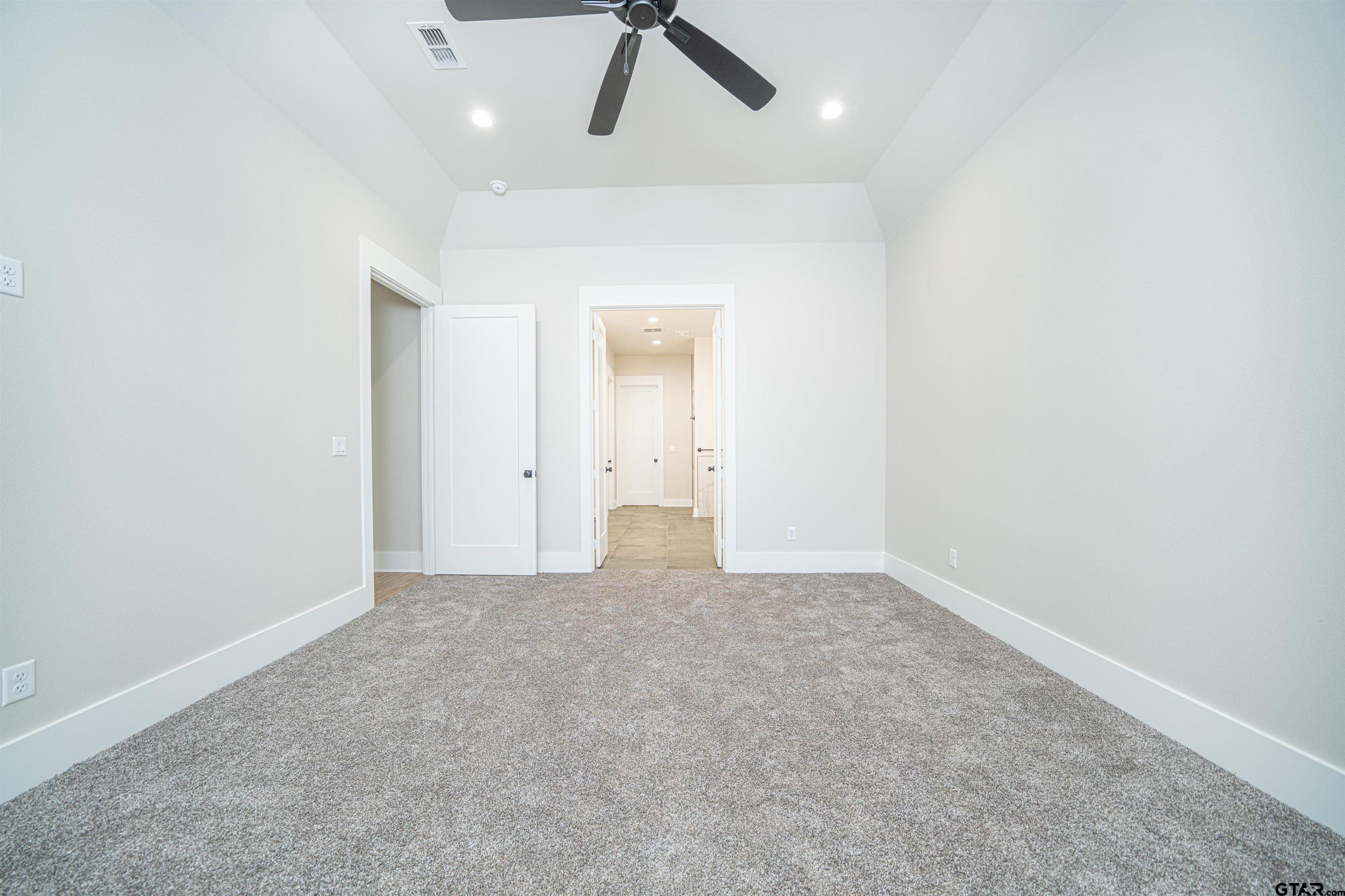 3910 Hidden Hills Circle Longview, TX 75605 - Photo 16 of 39 an empty room with a ceiling fan and carpet