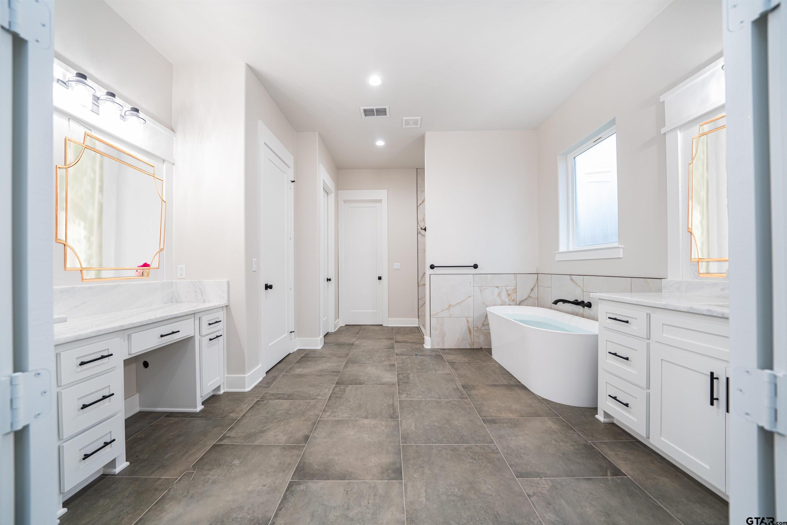 3910 Hidden Hills Circle Longview, TX 75605 - Photo 17 of 39 a large white bathroom with a granite countertop double vanity sink a mirror and a bathtub