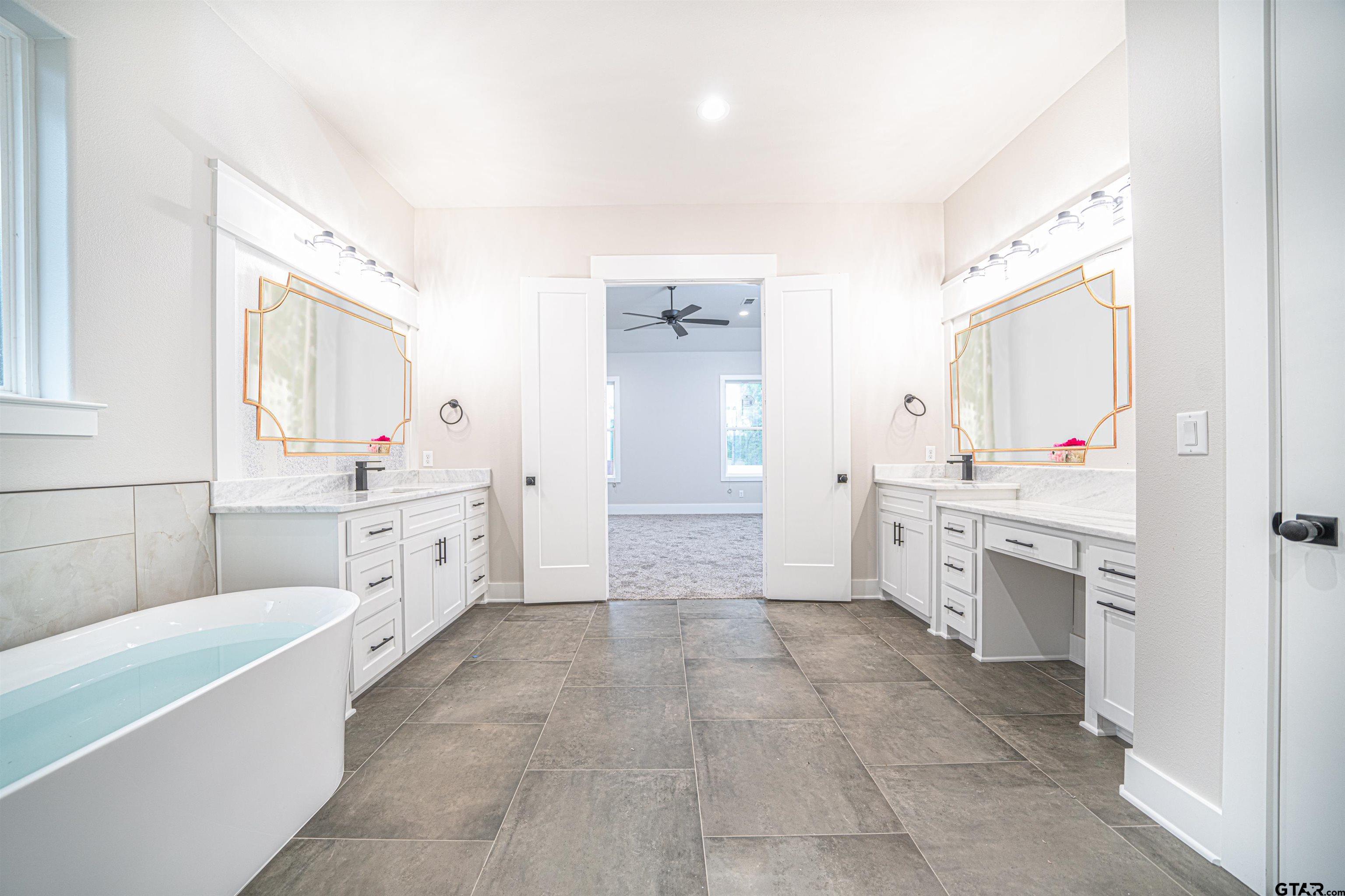 3910 Hidden Hills Circle Longview, TX 75605 - Photo 20 of 39 a large white bathroom with a granite countertop double vanity sink a mirror a bathtub and a shower