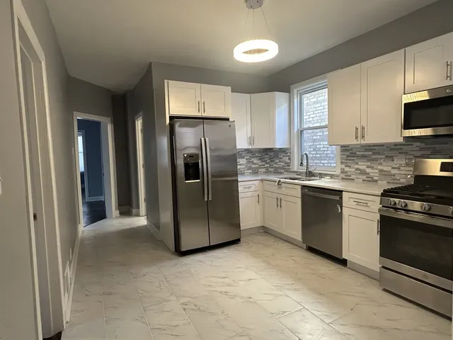 a kitchen with stainless steel appliances granite countertop a refrigerator a stove a sink and a microwave