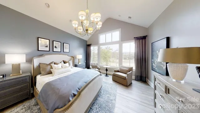 a bedroom with a bed couches and large windows