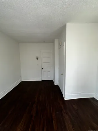 a view of an empty room with wooden floor and closet