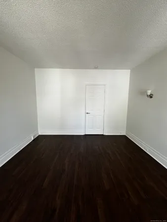 a view of an empty room with wooden floor and a sink