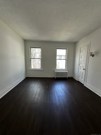 a view of an empty room with wooden floor and windows