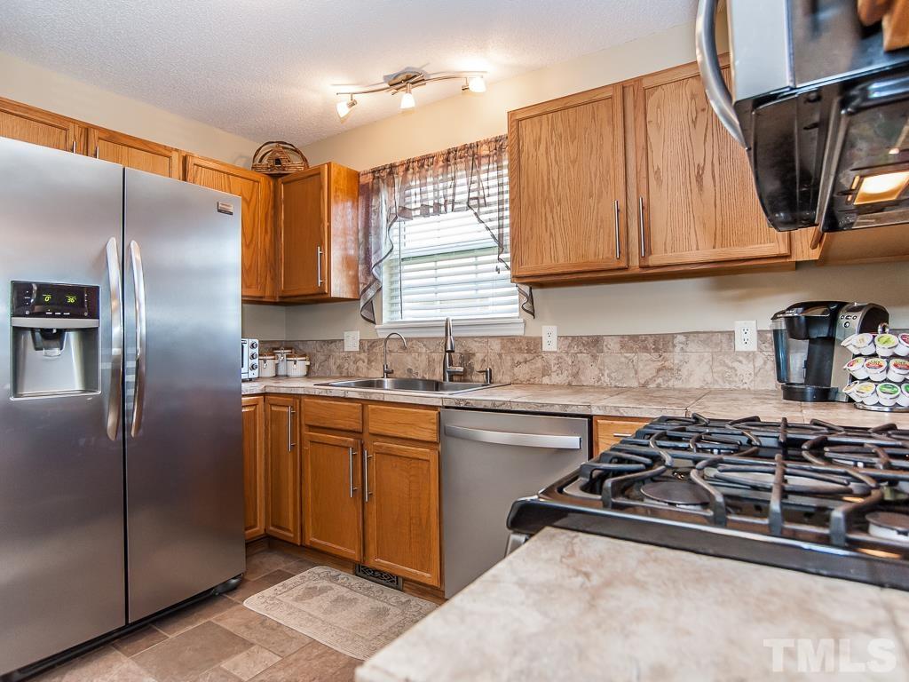 4217 Mardela Spring Drive Raleigh, NC 27616 - Photo 12 of 26 a kitchen with stainless steel appliances granite countertop a sink stove and refrigerator