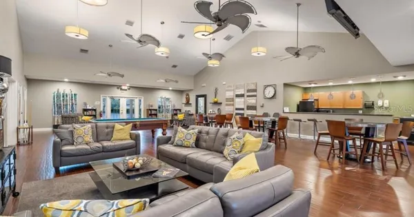 a living room with furniture kitchen view and a wooden floor