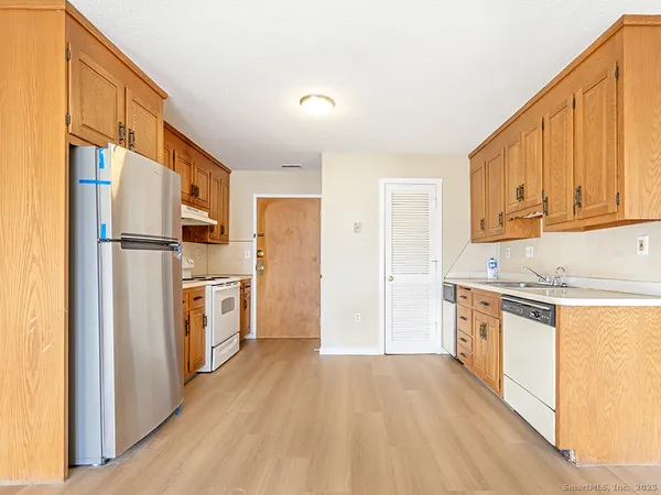 a kitchen with stainless steel appliances a refrigerator a stove a sink and white cabinets with wooden floor