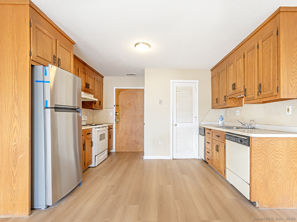 50 Long Street, Unit 5 New Britain, CT 06051 - Photo 8 of 16 a kitchen with stainless steel appliances a refrigerator a stove a sink and white cabinets with wooden floor