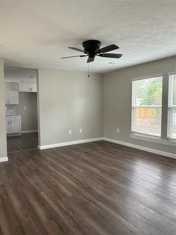 an empty room with wooden floor fan and windows