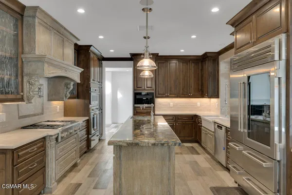 a kitchen with stainless steel appliances granite countertop a refrigerator a stove and a sink