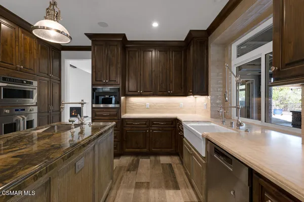 a kitchen with stainless steel appliances granite countertop wooden cabinets a stove top oven a granite counter top and stainless steel appliances