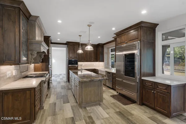 a kitchen with stainless steel appliances granite countertop a sink a stove and a refrigerator