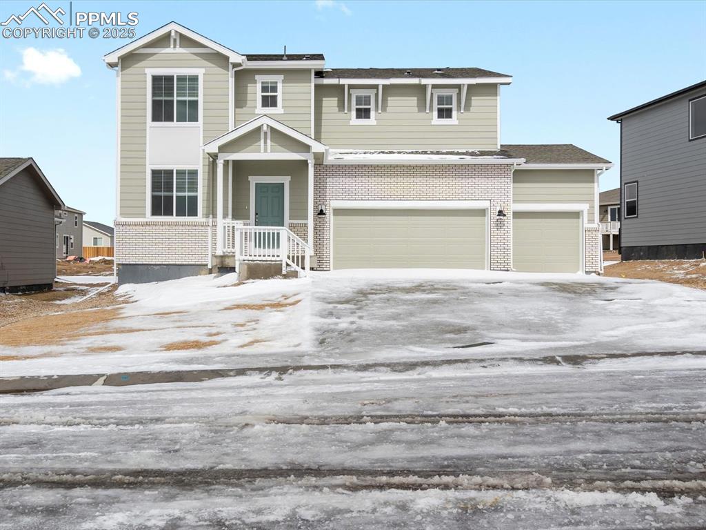 View of front of house with brick siding, an attached garage, and driveway