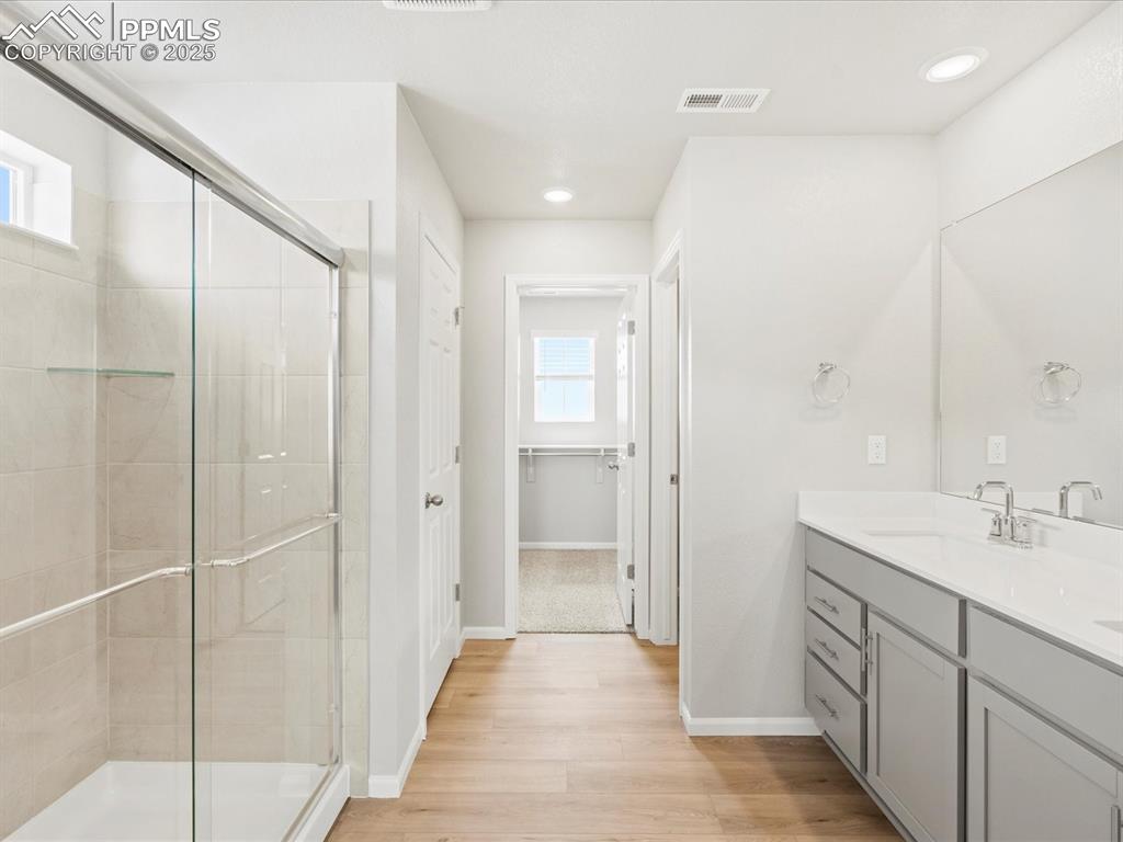 10636 Waterloo Drive Peyton, CO 80831 - Photo 22 of 36 Full bathroom featuring visible vents, a stall shower, wood finished floors, baseboards, and vanity
