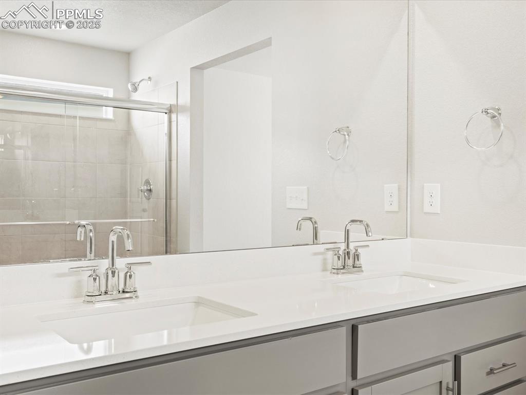 10636 Waterloo Drive Peyton, CO 80831 - Photo 24 of 36 Full bathroom featuring double vanity, a stall shower, a textured ceiling, and a sink