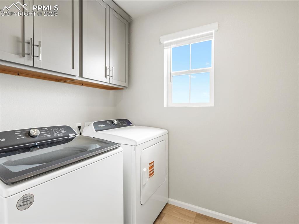 10636 Waterloo Drive Peyton, CO 80831 - Photo 33 of 36 Clothes washing area featuring light wood-style floors, cabinet space, baseboards, and washing machine and clothes dryer