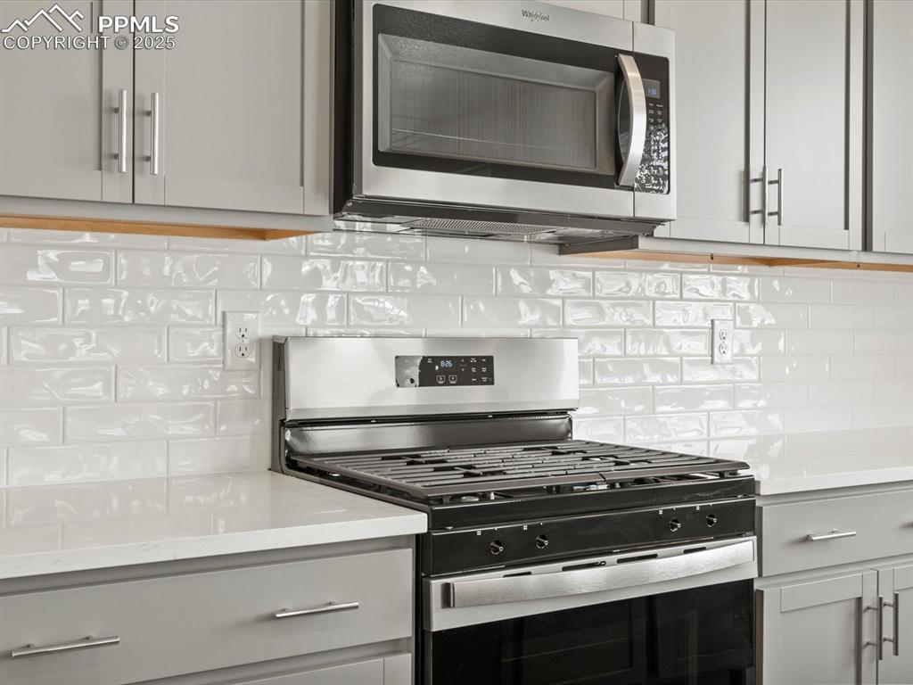 10636 Waterloo Drive Peyton, CO 80831 - Photo 10 of 36 Kitchen featuring decorative backsplash, gray cabinets, appliances with stainless steel finishes, and light countertops