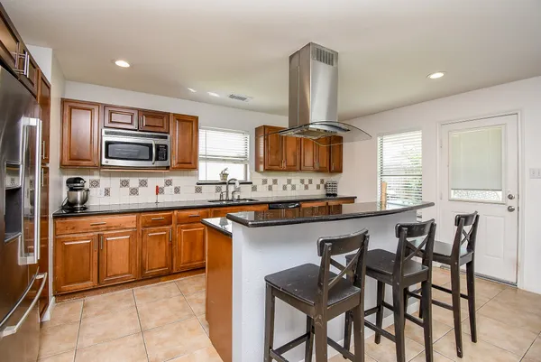 a kitchen with stainless steel appliances granite countertop wooden cabinets a stove a sink and a microwave