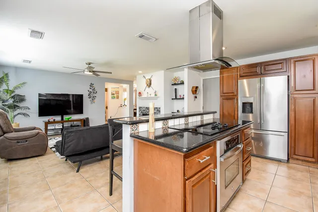 a kitchen with stainless steel appliances granite countertop wooden cabinets a stove a sink and a microwave