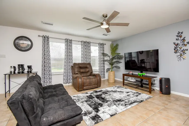 a living room with furniture kitchen view and a large window
