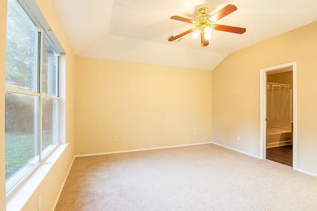 an empty room with windows and fan